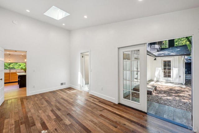 spare room with hardwood / wood-style flooring, recessed lighting, visible vents, and a skylight