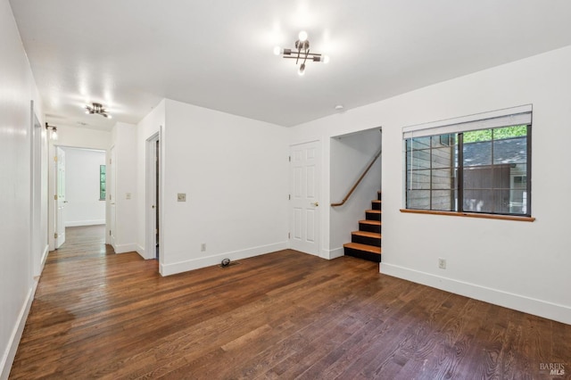 unfurnished room with stairway, baseboards, and dark wood-type flooring