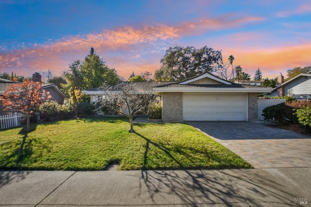 ranch-style home with brick siding, fence, decorative driveway, a garage, and a front lawn