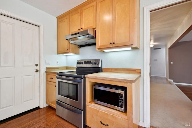 kitchen featuring appliances with stainless steel finishes, light brown cabinets, baseboards, under cabinet range hood, and butcher block countertops