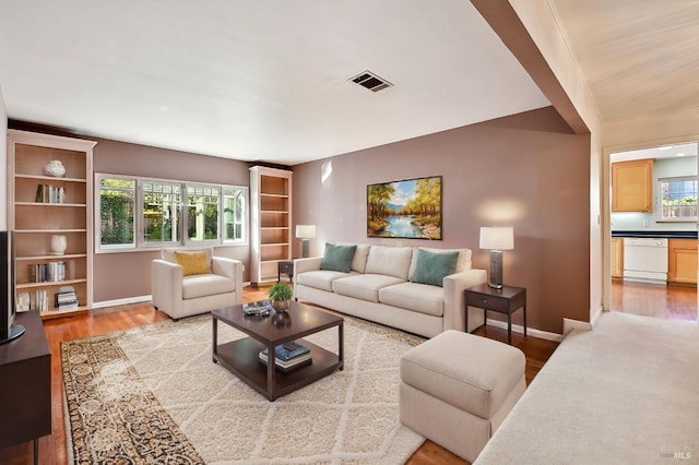 living area with baseboards, visible vents, and wood finished floors