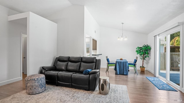 living room with a chandelier, lofted ceiling, baseboards, and wood finished floors