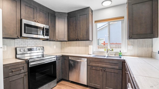kitchen featuring light countertops, dark brown cabinets, stainless steel appliances, and a sink