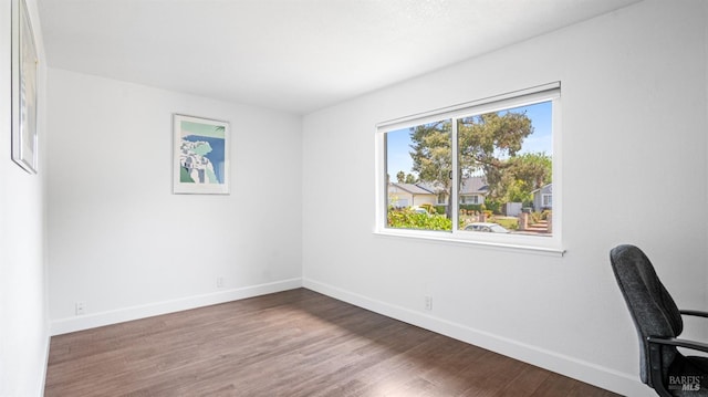 unfurnished office featuring baseboards and wood finished floors