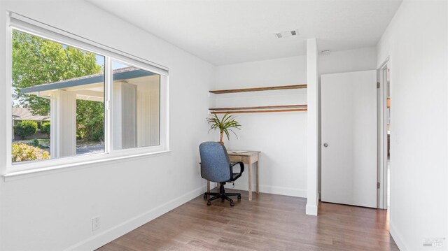 unfurnished office featuring visible vents, baseboards, and wood finished floors