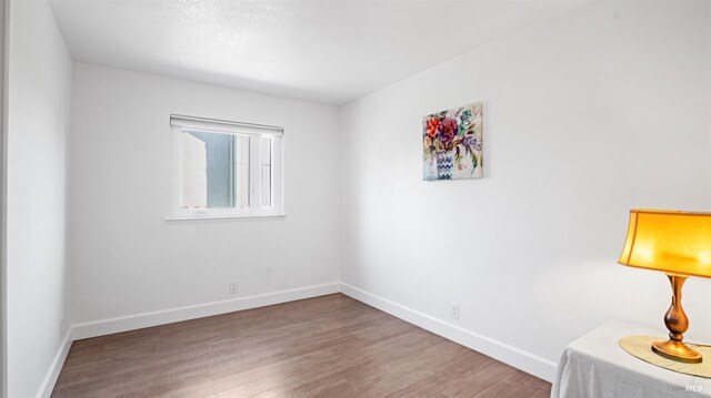 empty room with baseboards and wood finished floors