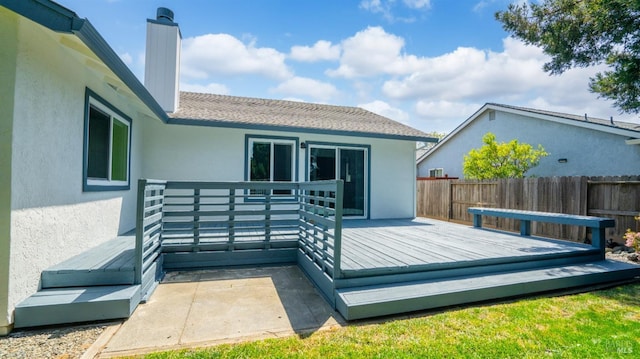 back of property featuring fence, a wooden deck, a chimney, and stucco siding