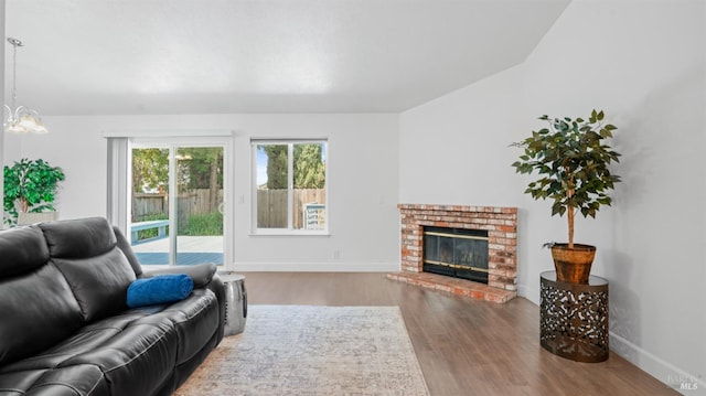 living room featuring a fireplace, wood finished floors, baseboards, and a notable chandelier