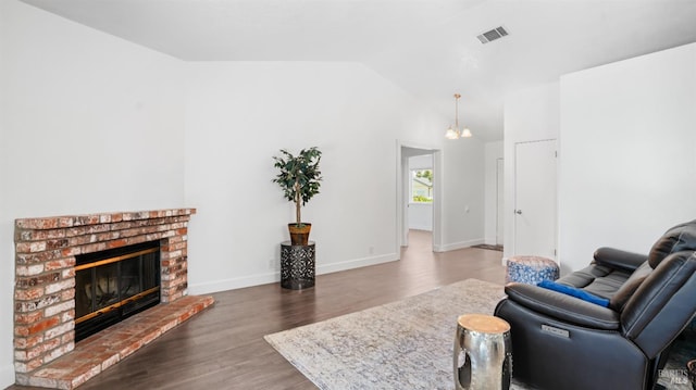 living area with lofted ceiling, wood finished floors, visible vents, and a fireplace