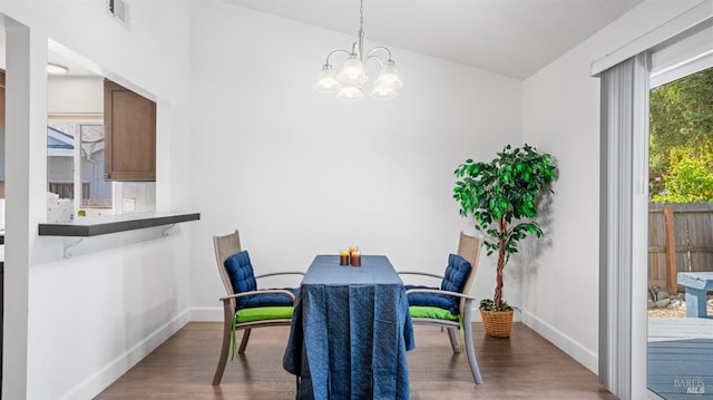 dining space featuring baseboards, wood finished floors, visible vents, and a notable chandelier