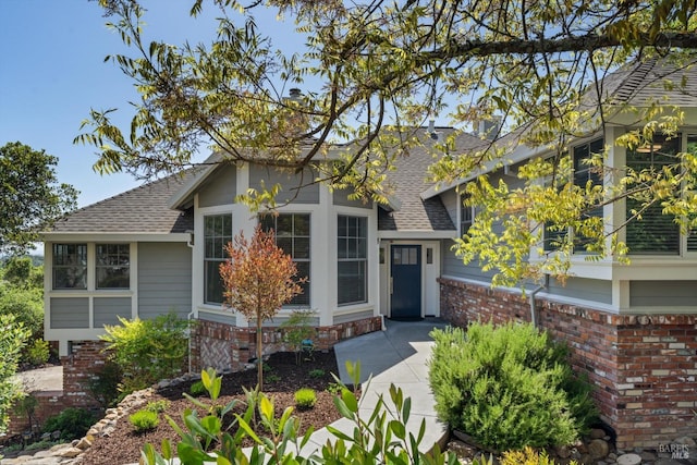 view of front facade with a shingled roof and brick siding