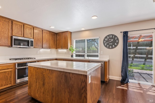 kitchen with tile counters, recessed lighting, appliances with stainless steel finishes, and dark wood finished floors