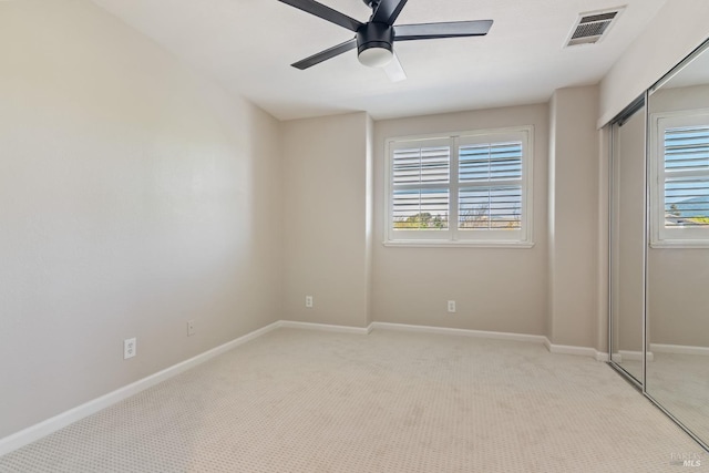 unfurnished bedroom with visible vents, light carpet, a closet, baseboards, and ceiling fan