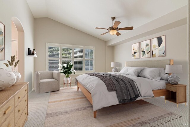 bedroom with ceiling fan, arched walkways, light carpet, and lofted ceiling