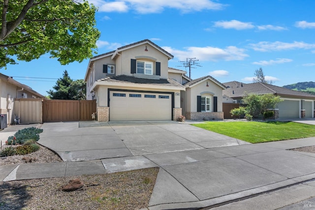 traditional-style home featuring driveway, an attached garage, fence, a front yard, and stucco siding