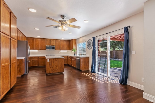 kitchen with stainless steel appliances, brown cabinets, ceiling fan, light countertops, and a kitchen island