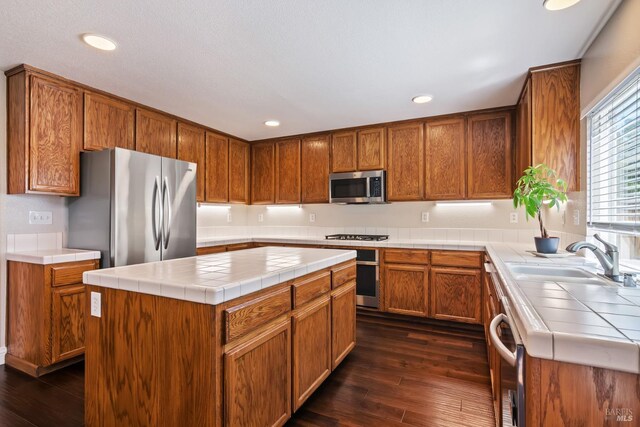 kitchen with tile countertops, stainless steel appliances, dark wood-style floors, and a sink