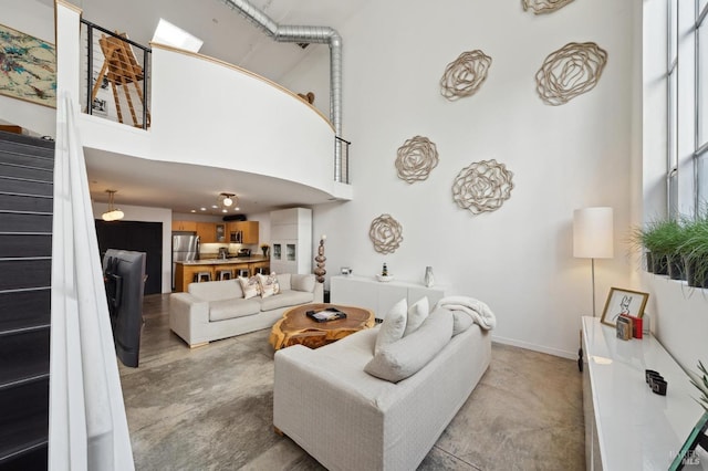 living room featuring stairway, a towering ceiling, and baseboards