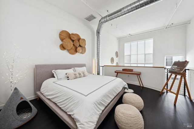 bedroom with wood finished floors, visible vents, and baseboards