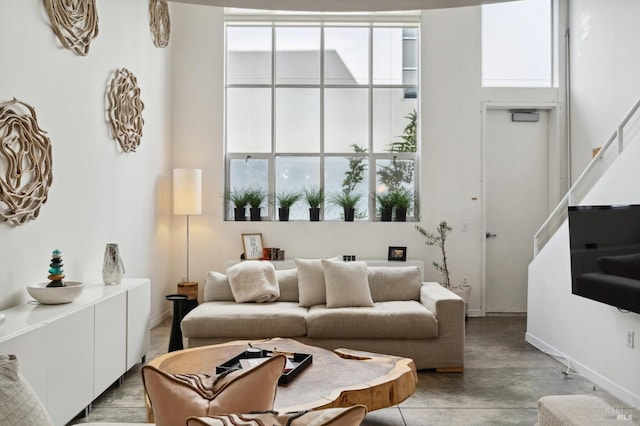 living area featuring stairway, a towering ceiling, and baseboards