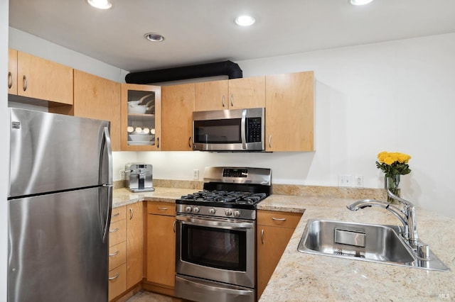 kitchen featuring recessed lighting, light brown cabinetry, a sink, glass insert cabinets, and appliances with stainless steel finishes