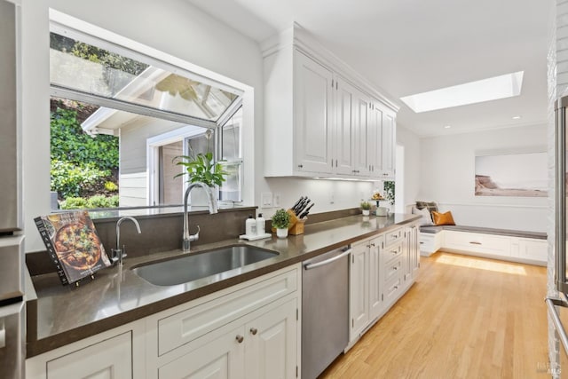 90 Corte Placida, Greenbrae, CA 94904 - kitchen featuring stainless steel dishwasher, a sink, a skylight, dark countertops, and white cabinets