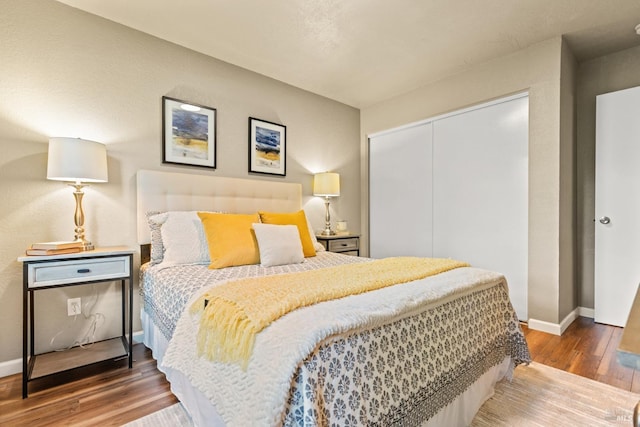 bedroom featuring wood finished floors, baseboards, and a closet