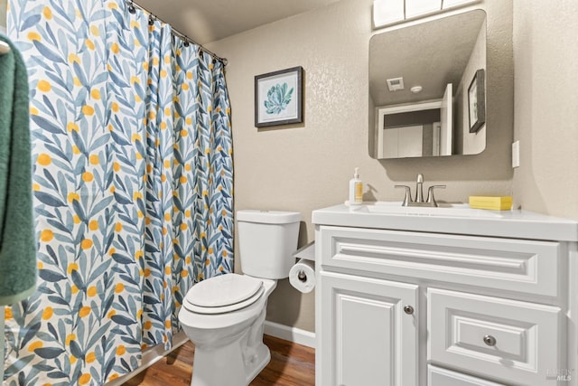 full bathroom featuring toilet, wood finished floors, curtained shower, a textured wall, and vanity