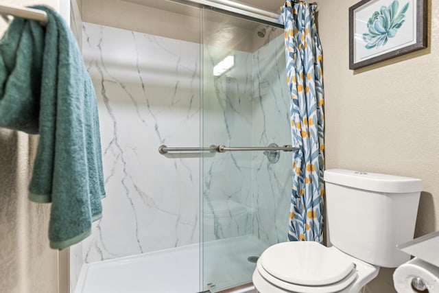 bathroom with a marble finish shower and toilet