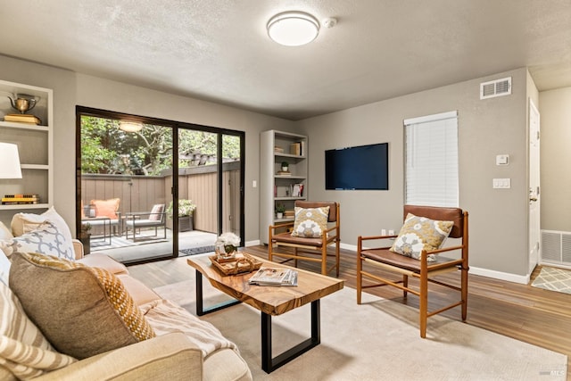 living area featuring wood finished floors, visible vents, and baseboards