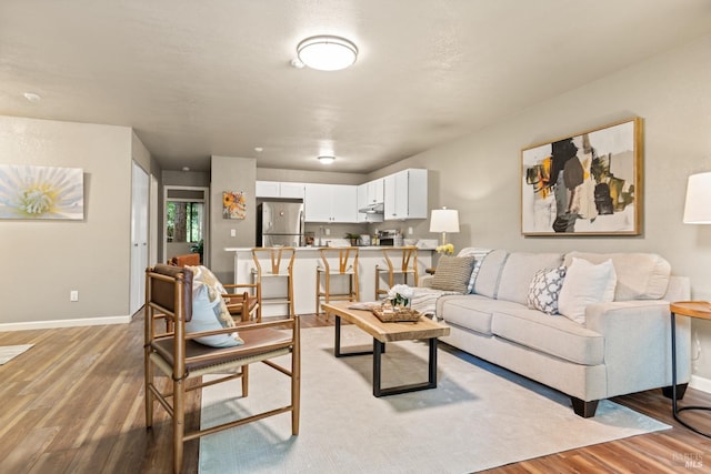 living area featuring baseboards and light wood-type flooring
