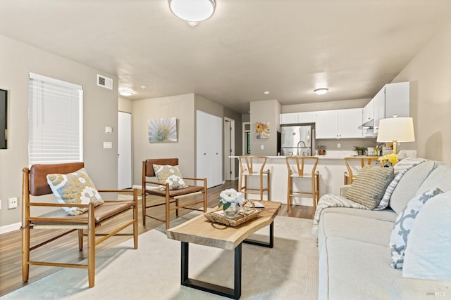 living area featuring light wood-type flooring, visible vents, and baseboards