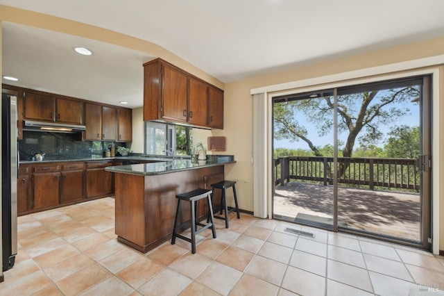 kitchen featuring dark countertops, a wealth of natural light, visible vents, and under cabinet range hood