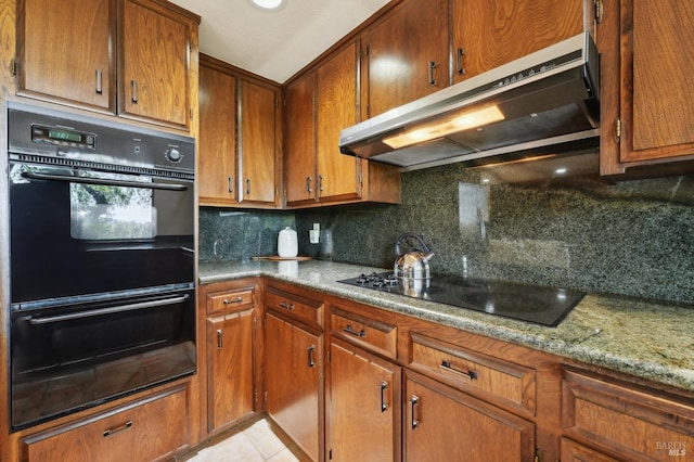 kitchen featuring black appliances, brown cabinets, decorative backsplash, and under cabinet range hood
