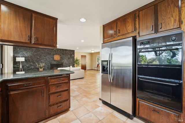 kitchen featuring recessed lighting, light tile patterned floors, stainless steel fridge with ice dispenser, dobule oven black, and backsplash
