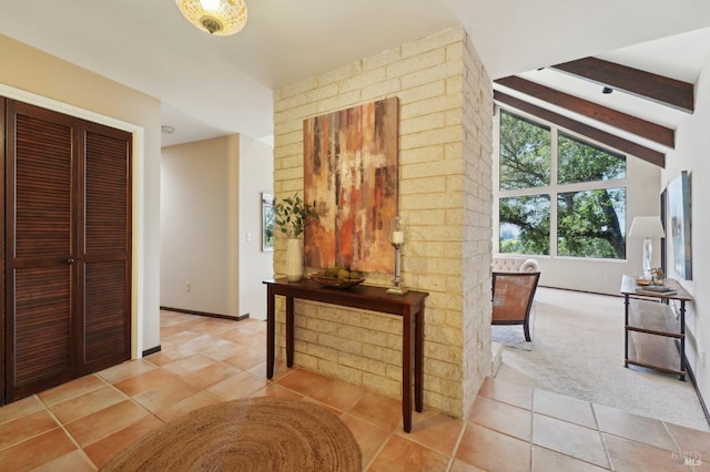 corridor featuring beam ceiling, baseboards, and light tile patterned floors