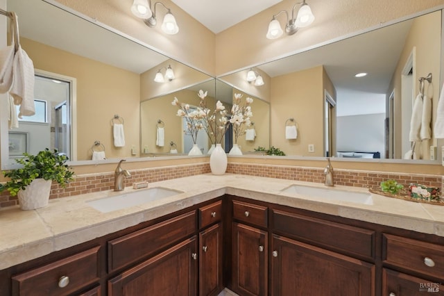 full bathroom with double vanity, an enclosed shower, tasteful backsplash, and a sink