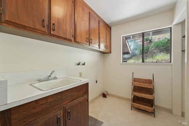 laundry room featuring hookup for a washing machine, cabinet space, hookup for an electric dryer, a sink, and baseboards