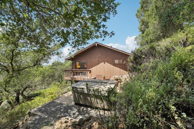 rear view of property with a wooden deck and a hot tub