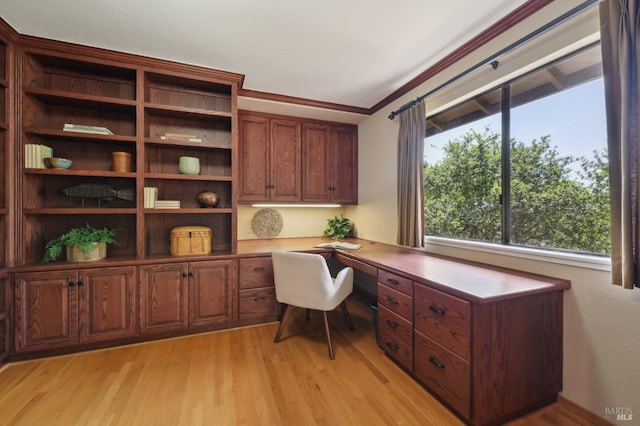 office area featuring ornamental molding, light wood finished floors, and built in study area