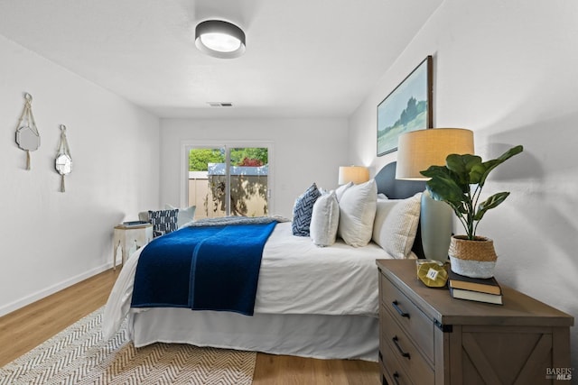 bedroom with wood finished floors, visible vents, and baseboards