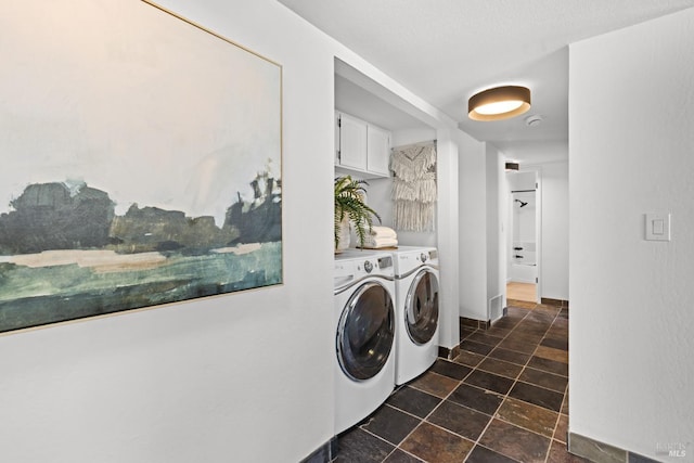 clothes washing area with visible vents, stone finish flooring, cabinet space, and washing machine and dryer