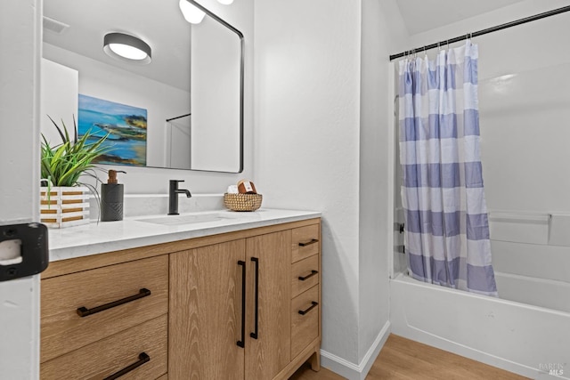 bathroom with wood finished floors, shower / bath combo with shower curtain, vanity, baseboards, and visible vents