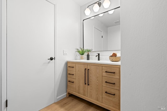 bathroom with vanity, visible vents, and wood finished floors
