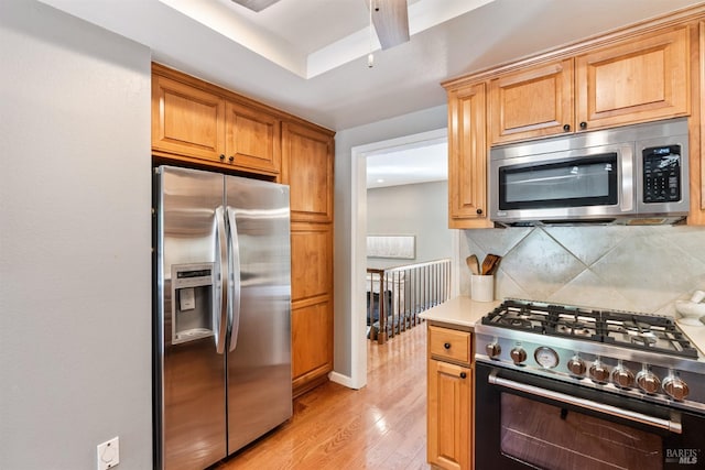 kitchen featuring decorative backsplash, light wood-style floors, baseboards, light countertops, and appliances with stainless steel finishes