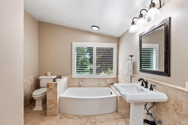 bathroom featuring tile walls, a bath, toilet, wainscoting, and lofted ceiling