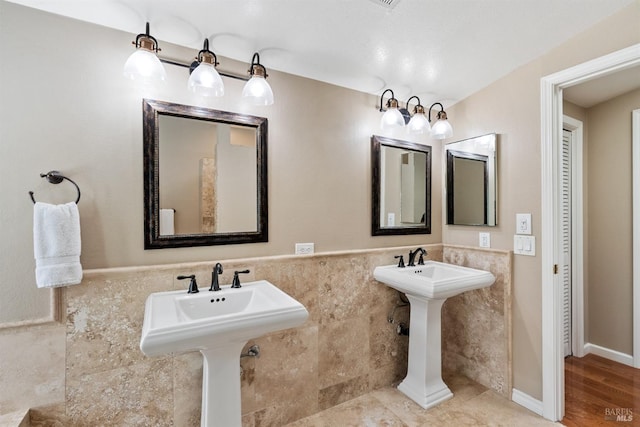 bathroom with tile walls, a sink, and wainscoting