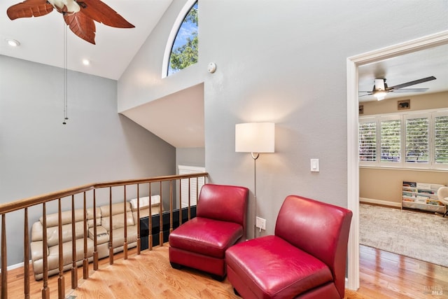 living area featuring an upstairs landing, ceiling fan, high vaulted ceiling, baseboards, and wood finished floors