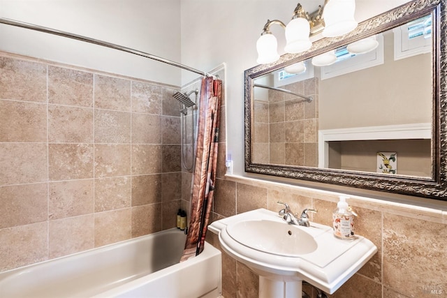 full bath with a sink, shower / bath combo with shower curtain, decorative backsplash, and tile walls