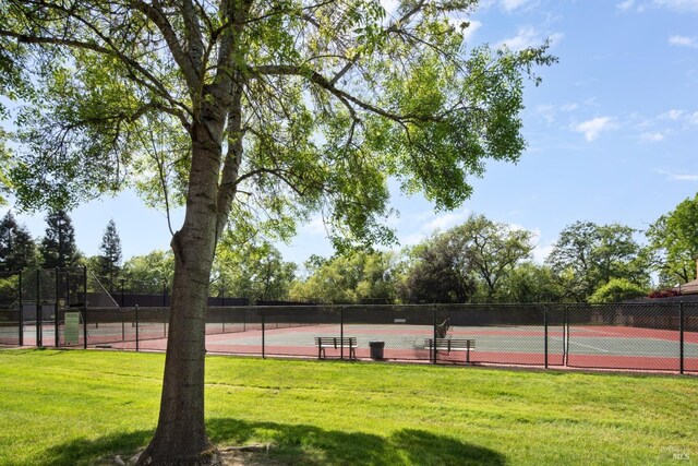 view of sport court with a yard and fence